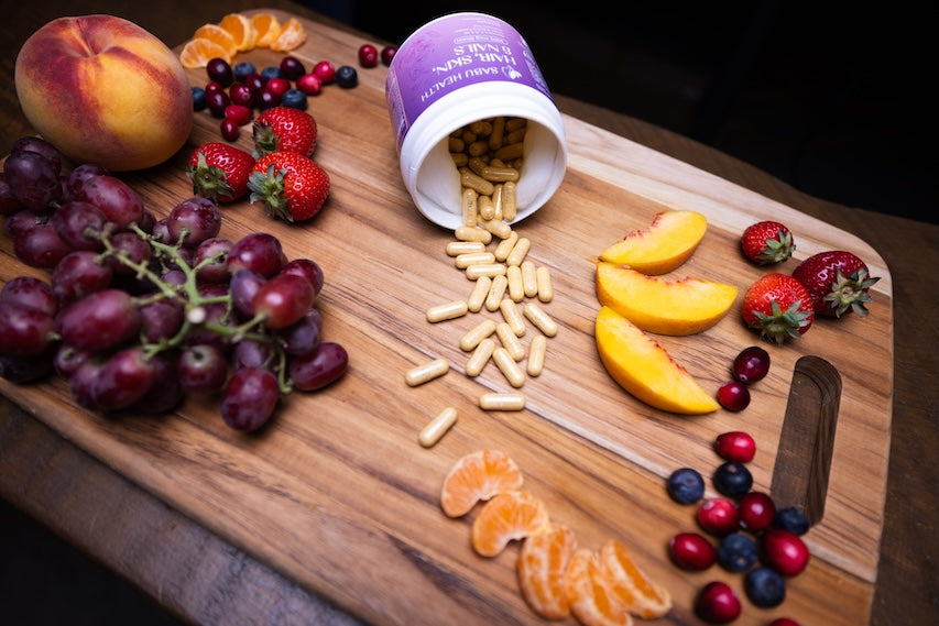 Wooden cutting board with fruits and a container of pills spilling out.
