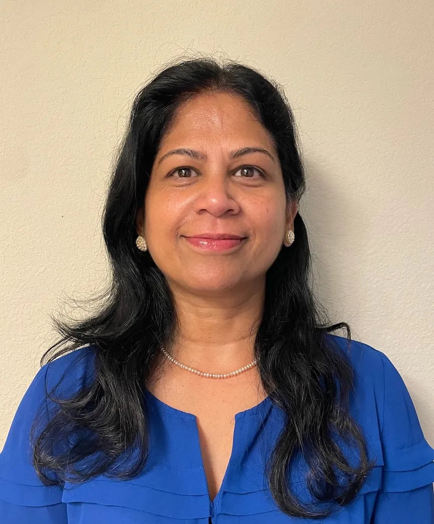 Woman with long dark hair wearing a blue shirt against a beige background